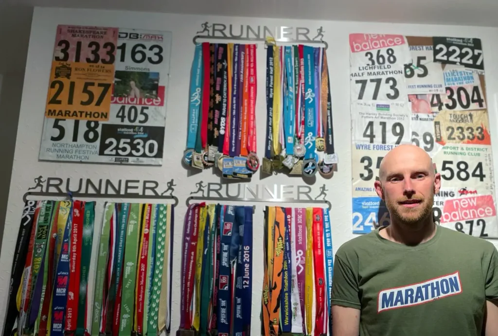 Lee Simmons standing by his collection of medals